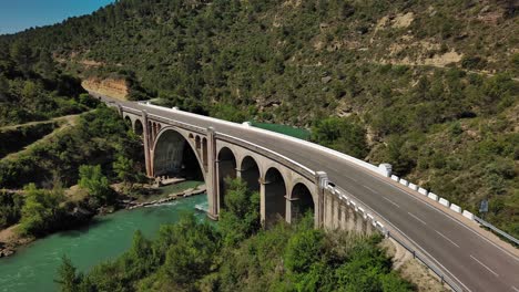 murillo de gallego bridge in huesca with cars passing over and turquoise river flowing underneath, sunny day, aerial view