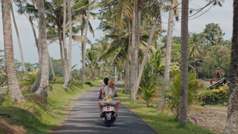 Pareja-De-Turistas-Montando-Motocicleta-En-Una-Isla-Tropical-Mujer-Feliz-Celebrando-La-Libertad-Con-Los-Brazos-Levantados-Disfrutando-De-Un-Viaje-De-Vacaciones-Con-Su-Novio-En-La-Vista-Trasera-De-Un-Paseo-En-Motocicleta