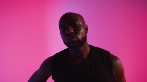 retrato de estudio en primer plano de un jugador de baloncesto masculino driblando y rebotando la pelota contra un fondo iluminado de color rosa 1