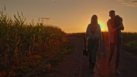 family walking through a cornfield at sunset