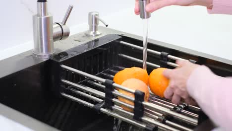 hands of a woman washing an apple over the kitchen sink preparing a fresh breakfast with fruit hands of a woman washing an apple over the kitchen sink preparing a fresh breakfast with fruit vegan food concept