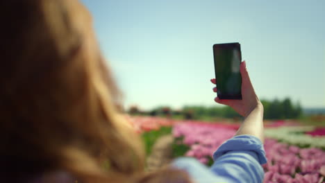 vista trasera de una mujer joven haciendo una selfie en el teléfono celular.