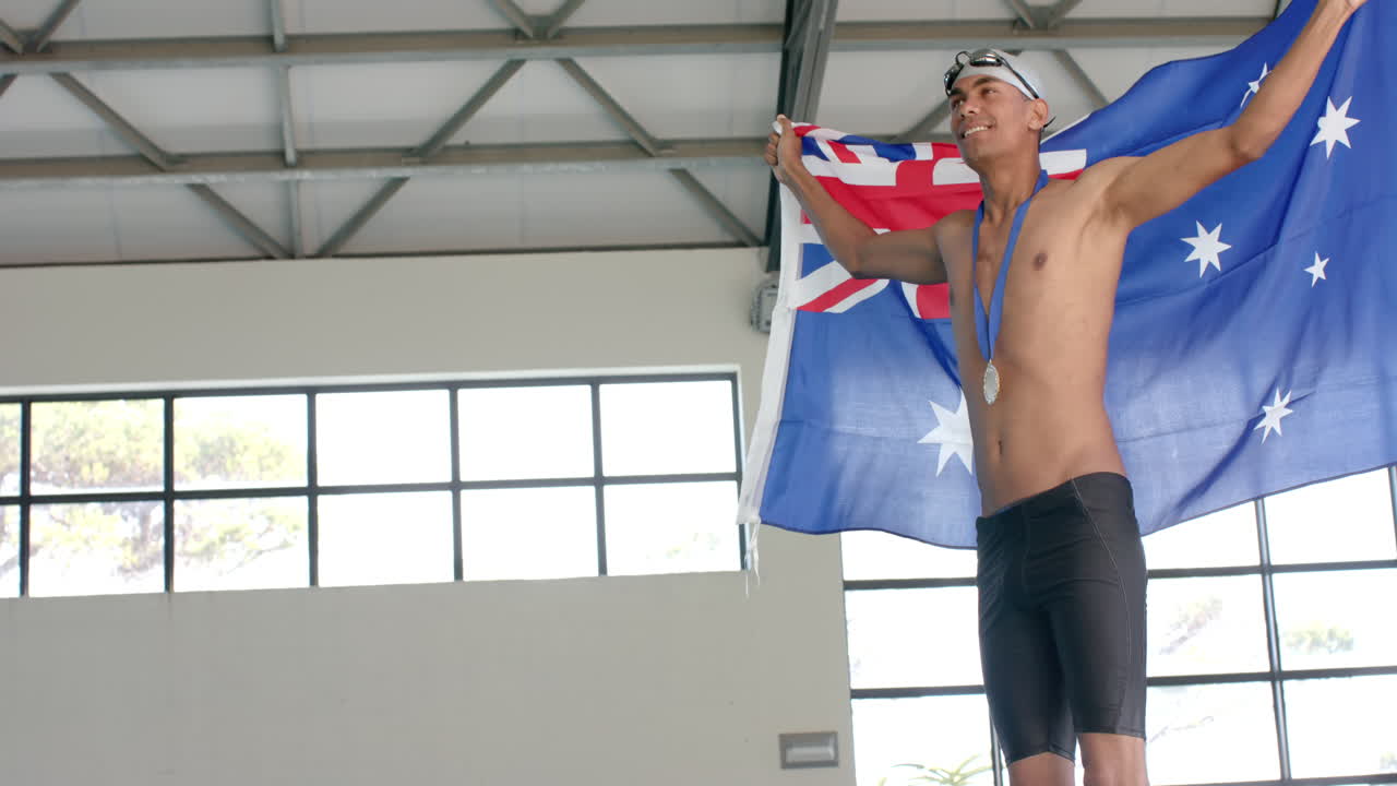 젊은 남성 남성 선수 수영 선수가 오스트레일리아 발을 들고 스포츠 행사에서 승리를 축하합니다.