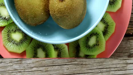 Kiwis-arranged-in-bowl-and-plate-on-wooden-table