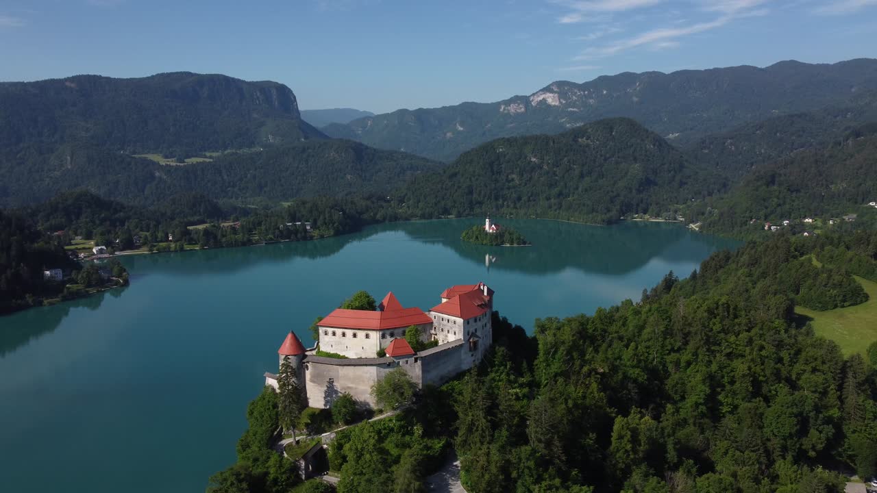 Panorama di lago glaciale alpino e castello con piccola isola. Filmato video stock di alta qualità 4K ripreso con drone.