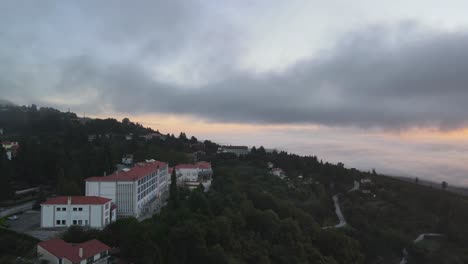 aerial forward over golden tulip caramulo hotel and surrounding landscape at sunrise on cloudy day, portugal