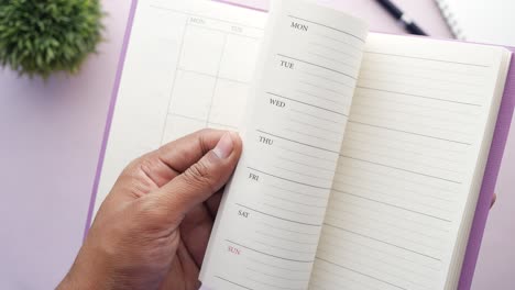 close up of mans hand turning a pager of a diary