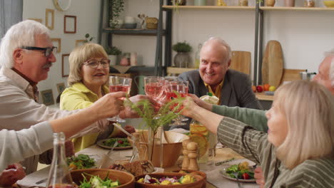 happy senior friends toasting with wine at dinner