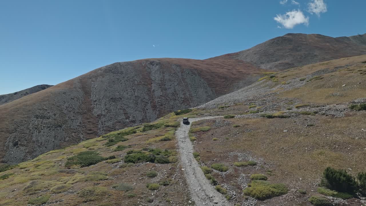 Panoramic orbit behind truck driving up along dirt road in grassy forest on Peak 10 trail Breckenridge Colorado
