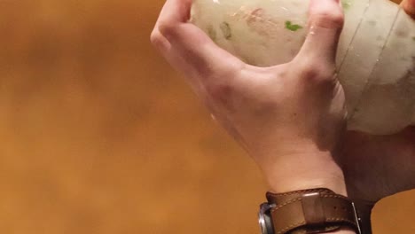 close-up of hands vigorously shaking a transparent bottle containing visible ingredients.