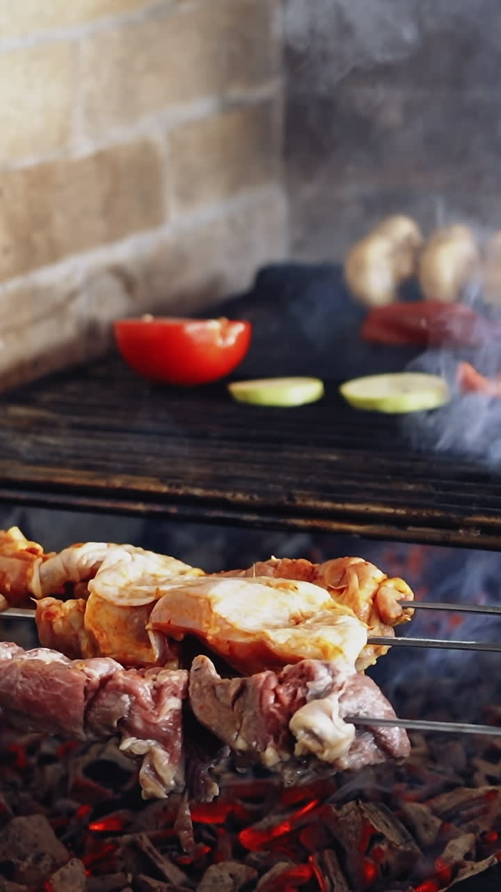 Grilling food. Barbecue. Hot grill with charcoals on the restaurant kitchen. Smoking grill frying meat and vegetables. Hand of a chef turning over grilled vegetables. Vertical video
