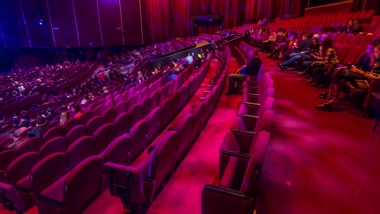 Spectators gather in the auditorium and watch the show in theatre timelapse. Large hall with red armchairs seats. Viewers filling places until turn off the light. View from right side