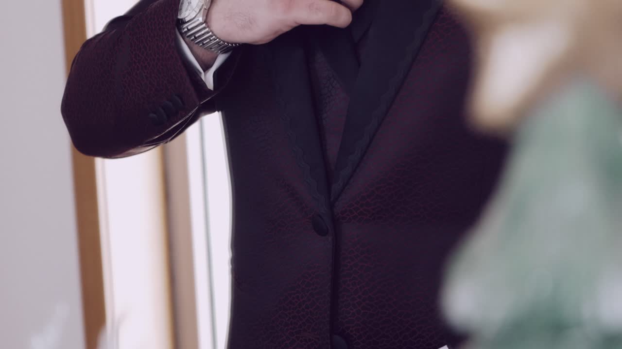 Close up of a man adjusting his elegant black tuxedo with a wristwatch