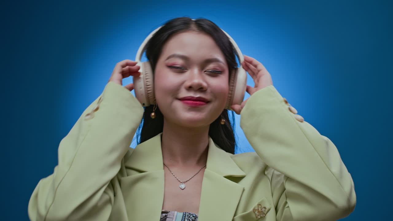 Young Woman Listening to Music in Headphones on Neon Blue Background