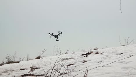 gran dron profesional dji inspire 2 con cámara de video vuela bajo sobre la nieve mientras sopla un fuerte viento
