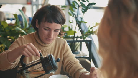 young woman talking to her friend and having a cup of tea