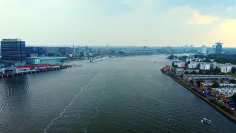 aerial view of the ij river with amsterdam centraal train station in the distance in amsterdam, netherlands.