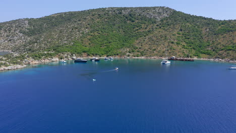 aerial: small boat with tourists approaches peristera island shipwreck beach in sporades, greece