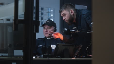 two security guards monitoring screens in a control room