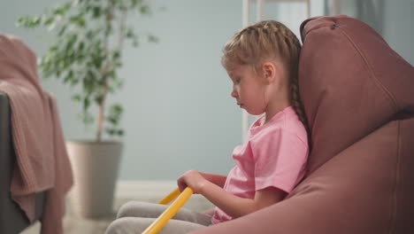 upset girl with gymnastic hoop sits in bean chair at home