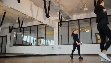 Young Female Trainer and Schoolgirl Doing Breathing Exercises During Training Warming Up. Young female trainer and schoolgirl doing breathing exercises during training. Warming up before ballet class. The concept of children’s extracurricular work