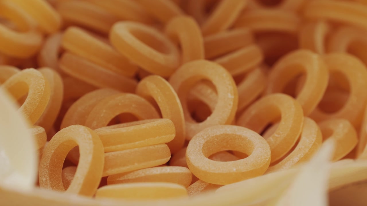 Pasta integrale biologica, maccheroni di semola di grano duro, penne rigate crude in una ciotola di legno. Filmato 4k di alta qualità