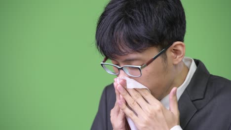 sick young asian businessman blowing nose on tissue