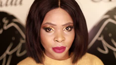 close-up portrait of a woman with bold gold eyeshadow and magenta lipstick