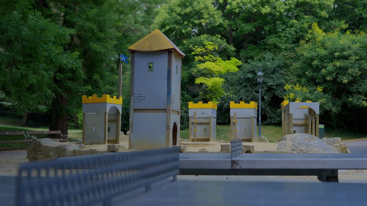 Children's playground with a sand and castle in the background and Table Tennis in the foreground at T&uuml;rkenschanzpark in Vienna during a sunny day at noon in slow motion