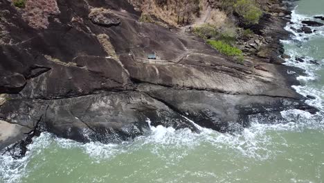 aerial of waves crashing onto rocks at trinity beach in cairns