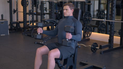 hombre atlético en forma haciendo curls de martillo con pesas en el gimnasio en cámara lenta