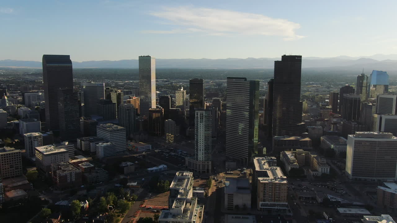 Backwards drone dolley shot of the modern skyline of Denver on a sunny day