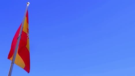 the flag of spain against a clear blue sky with copy space