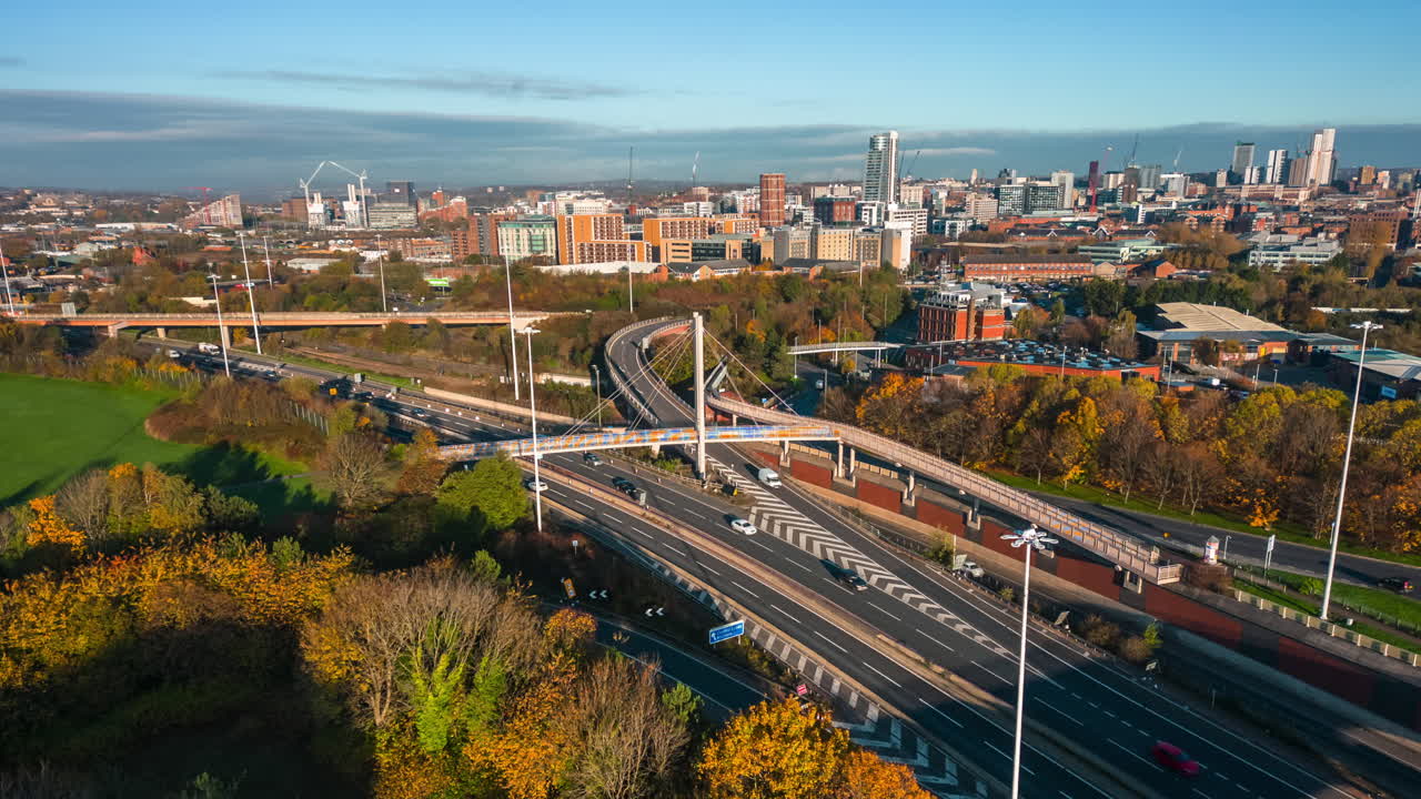 Hyperlapse e Motion Timelapse dell'autostrada M621 con il centro di Leeds sullo sfondo in autunno, volando sopra un condominio con traffico intenso sulle strade nel West Yorkshire, Regno Unito.