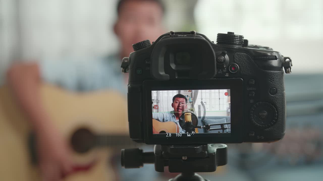 Man playing acoustic guitar for online performance