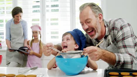 Padre-Ayudando-Al-Niño-A-Filtrar-La-Harina-Usando-Un-Colador