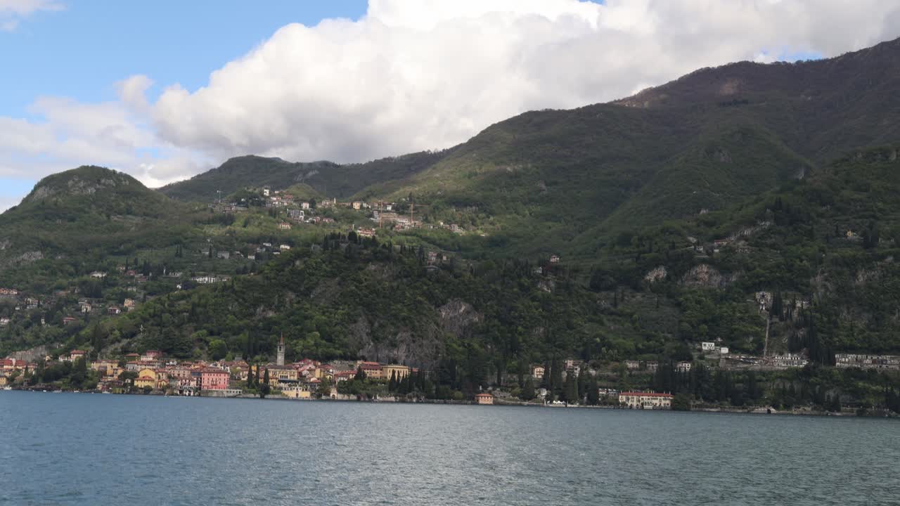 Crossing lake Como with colorful coastal towns below mountains