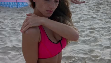 a young woman sits on the beach by the sea and rubs her arm with sunscreen on hot summer day