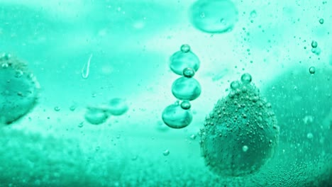 macro shot of sparkling blue bubbles falling to ground in bright blue water