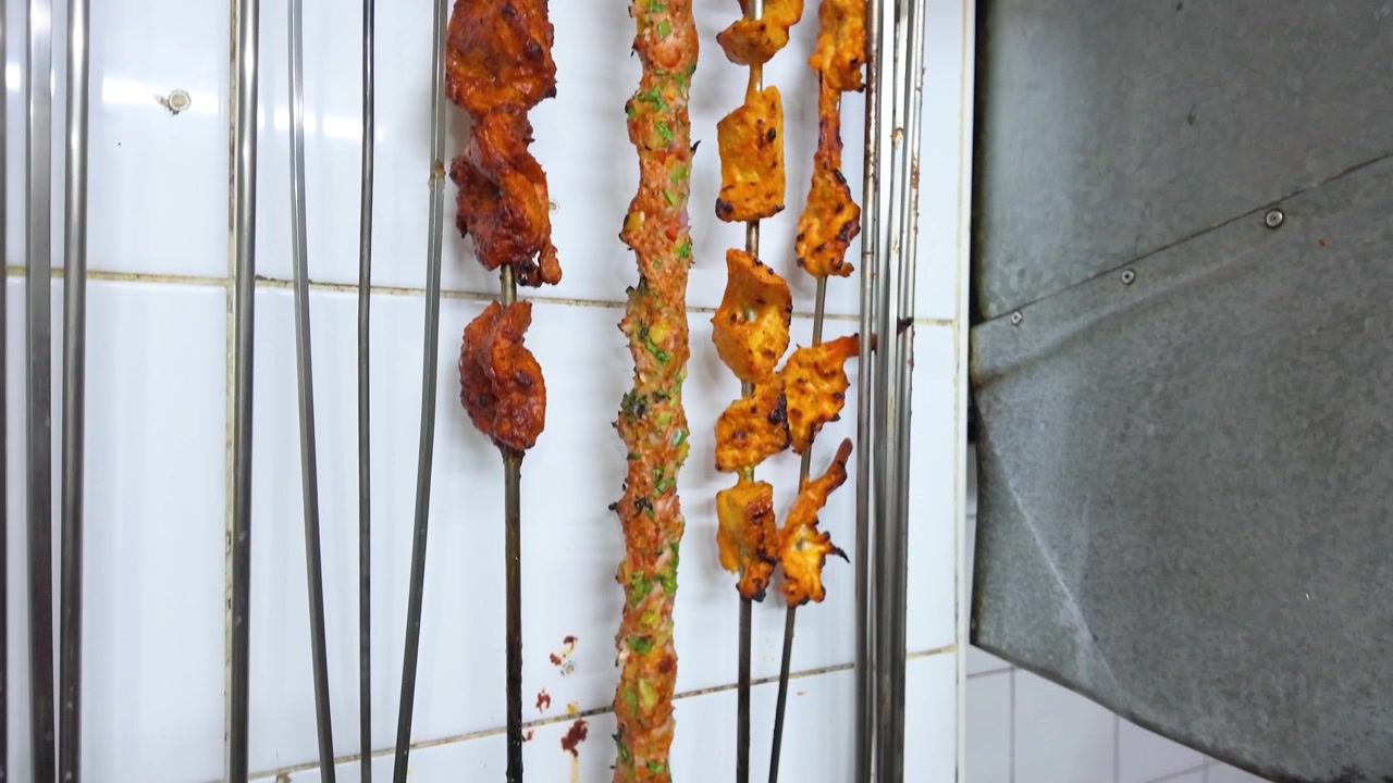 Spiedini di carne marinata e verdure appesi in una cucina di ristorante