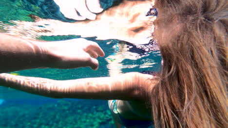 Hand-grabbing-an-arm-of-a-girl-floating-underwater-in-a-Hawaii-lagoon