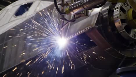 dynamic close-up of precision welding process on high-performance aerospace component featuring intense sparks and robotic arm technology