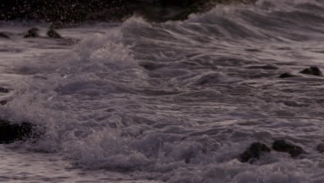 Primer-Plano-De-Las-Olas-Rodando-En-La-Playa-En-Hawaii,-Salpicando-Rocas-Al-Atardecer