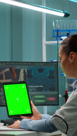 vertical video: microbiologist working on notepad with green chroma key display