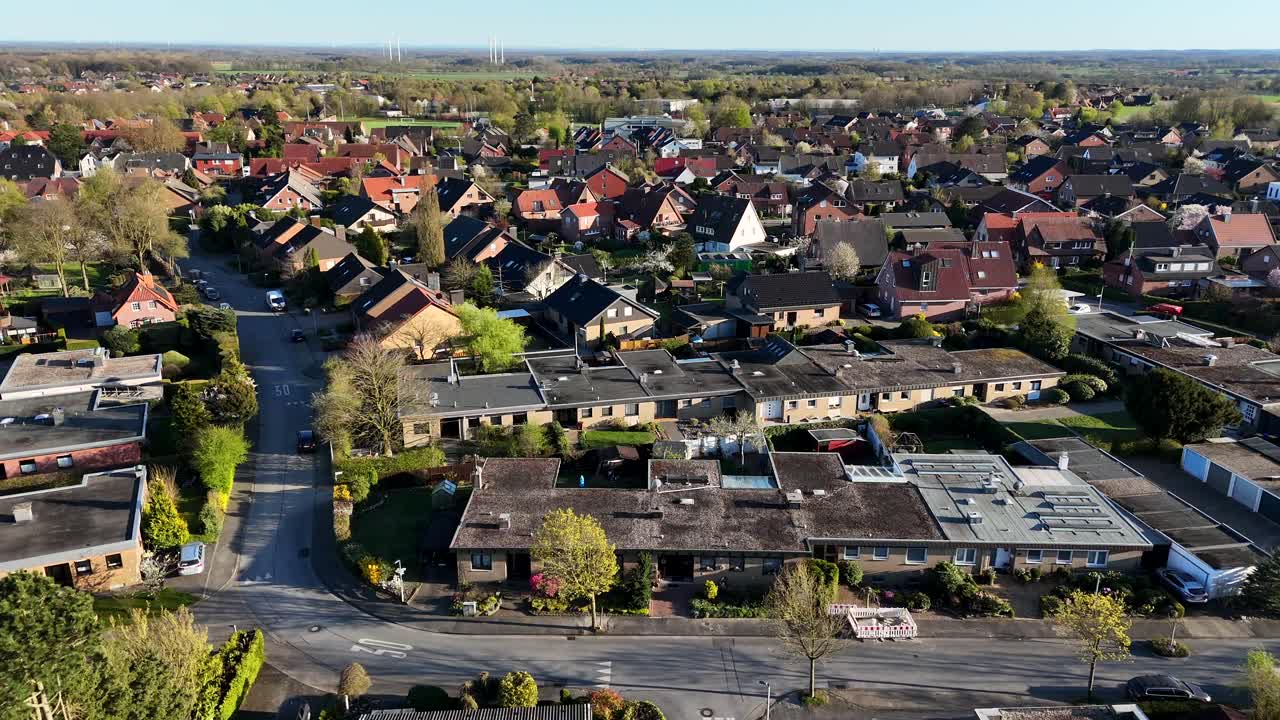 Single-story homes and townhouses during golden sunset in american town. Aerial lateral wide shot. Tree-lined trees blooming along peaceful street in american neighborhood.