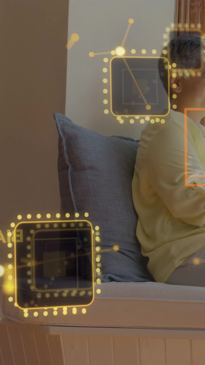 Vertical video: Seated mature woman shifting as yellow AR nodes entering frame and pulsing for tech