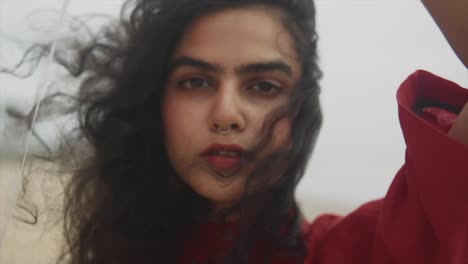 fotografía de cerca de una modelo de moda india con un vestido rojo y sosteniendo un globo rojo en cámara lenta en una playa de arena en goa, india