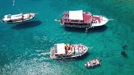 Drone-of-boats-parked-in-shallow-crystal-blue-waters-on-the-Turkish-Riviera-in-Bodrum-with-people-swimming