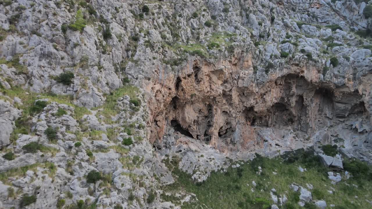 volando hacia la ladera de una montaña con agujeros en ellos en el cañón de sa calobra, mallorca, españa