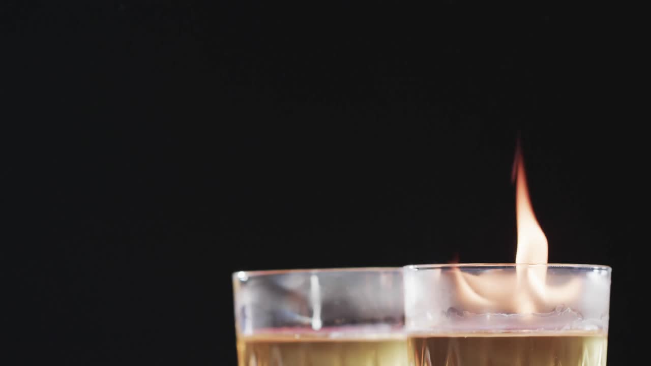 video de alcohol encendido en vasos con llamas de fuego amarillas y espacio de copia sobre fondo negro